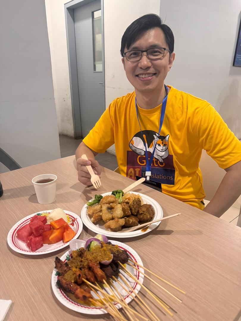 Przyjaciel Gato, David Wang, delektujący się satay na WordCamp Malaysia 2025
